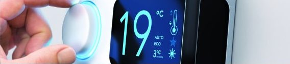 Hand bedient ein digitales Raumthermostat mit der Anzeige 19 Grad